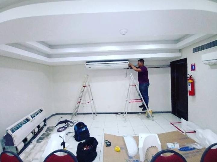 Técnico trabalhando em ar-condicionado em salão